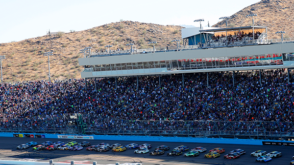 Cars on track at Phoenix Raceway with view of grandstands