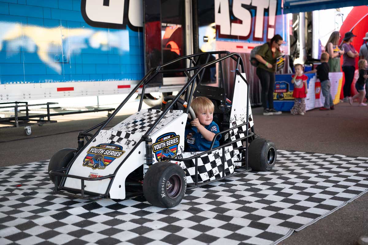 Child sitting in quarter midget race car at Phoenix Raceway inside the NASCAR Kids Club