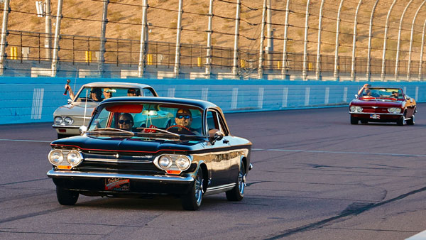 Promotional graphic for Phoenix Raceway Track Laps for Charity featuring a red sports car driving on the racetrack under bright stadium lights. Large text reads 